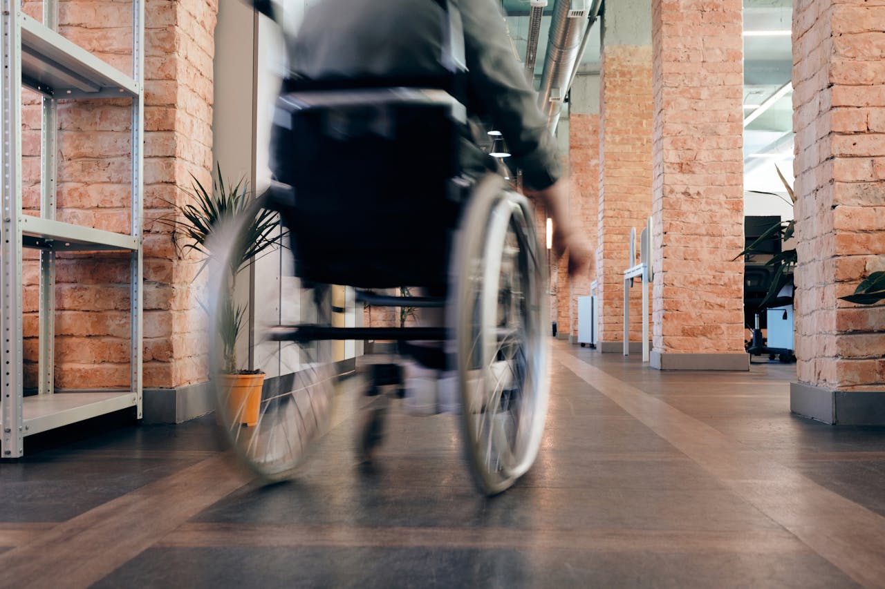 about-02 Blurred motion of a person in a wheelchair moving quickly through an indoor office hallway.