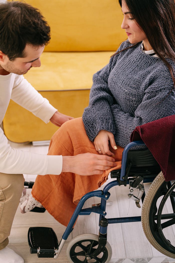 A supportive man assisting a woman in a wheelchair indoors, reflecting care and companionship.